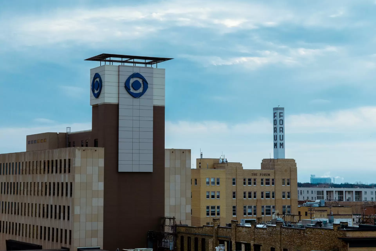  view of the Fargo, North Dakota skyline, featuring a mix of historic and modern buildings, including a prominent tower with a distinctive logo.