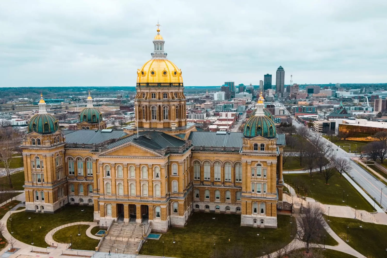 Aerial view of the Iowa State Capitol building in Des Moines, Iowa, with the city skyline in the background.