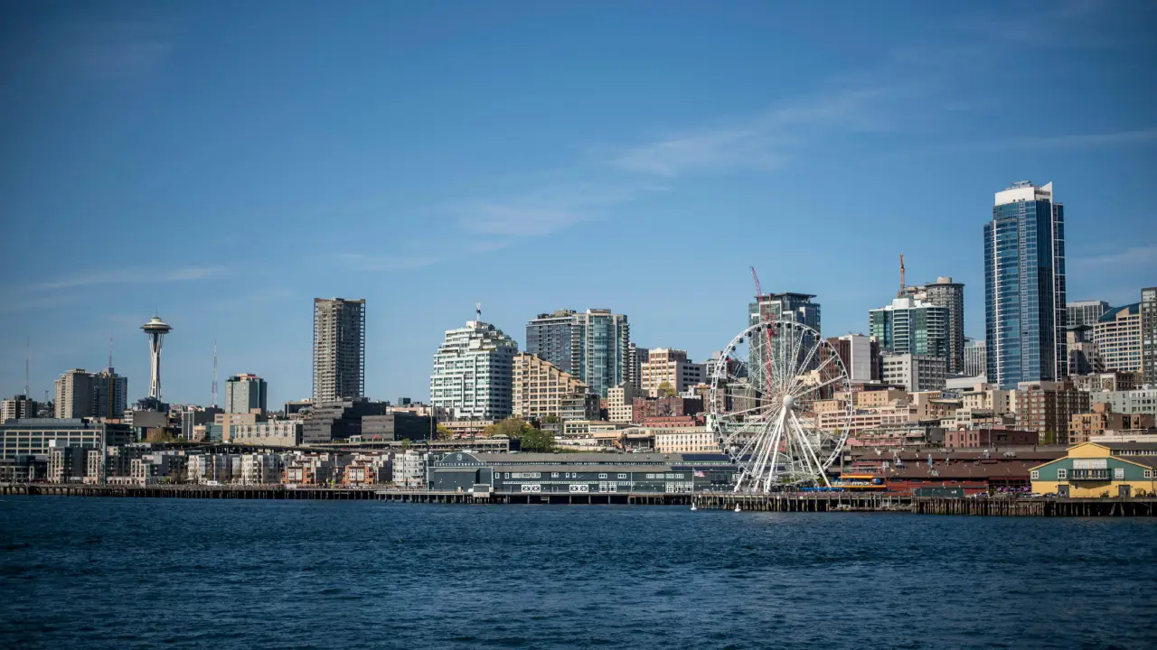 A scenic view of the Seattle skyline with the iconic Space Needle and the Great Wheel in the foreground.