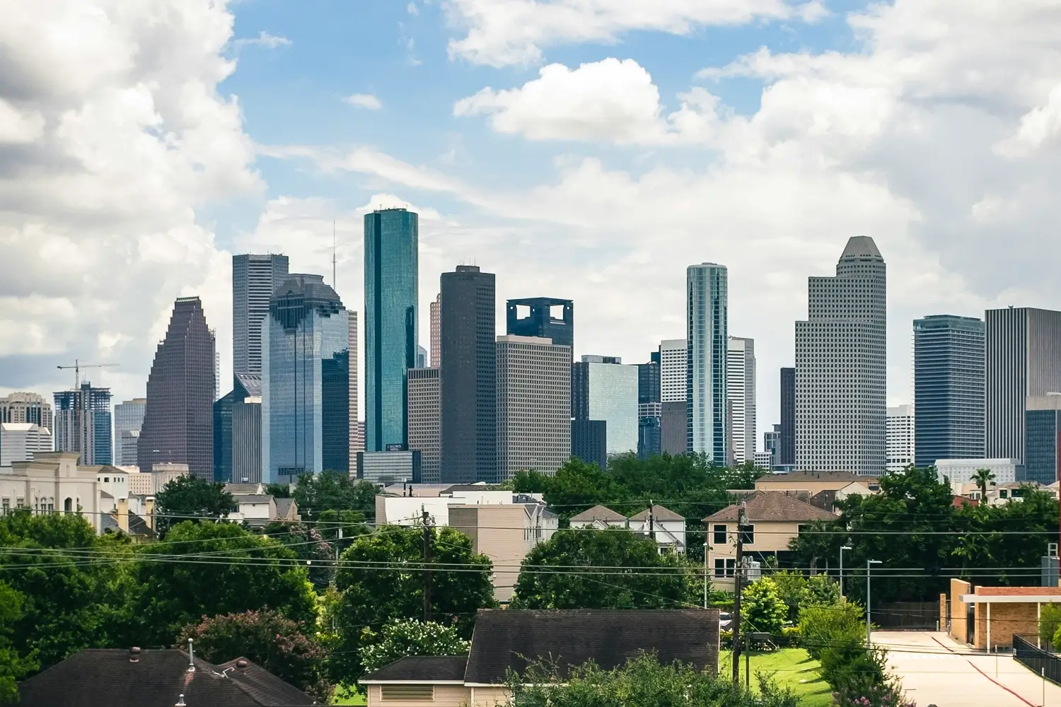 Downtown Houston skyline with modern skyscrapers and residential houses in the foreground.