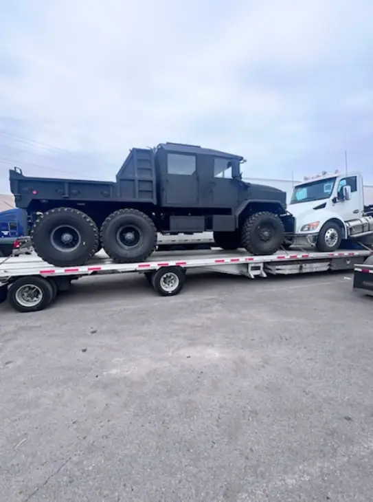 Military truck being transported on a flatbed trailer by AutoStar Transport Express