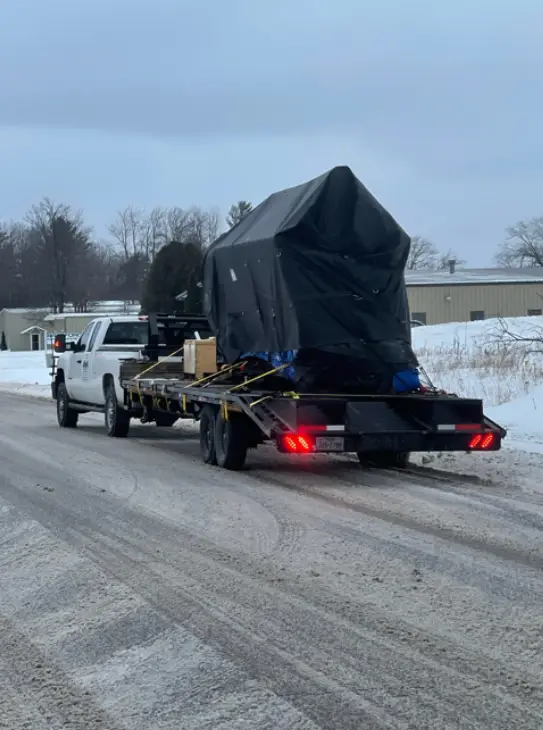 Professional auto transport truck delivering covered vehicle on flatbed trailer through winter conditions from Minnesota to Arizona.
