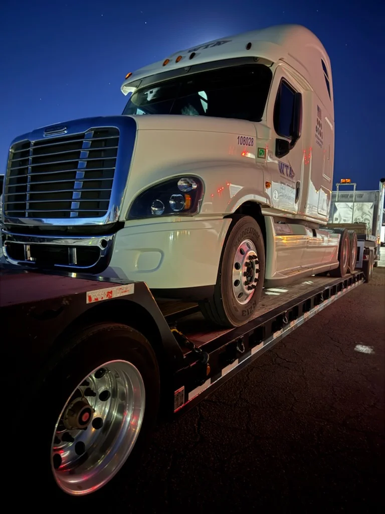 White semi-truck loaded on AutoStar Transport Express flatbed for secure heavy haul shipping