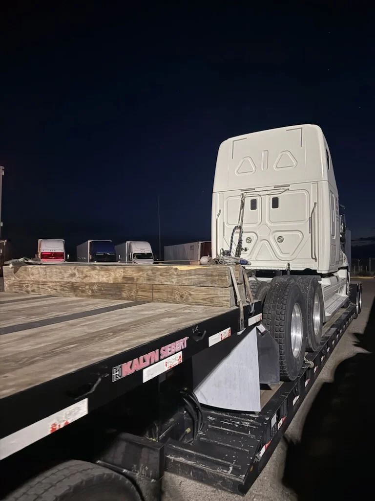 White semi-truck cab secured on AutoStar Transport Express flatbed for safe heavy equipment shipping