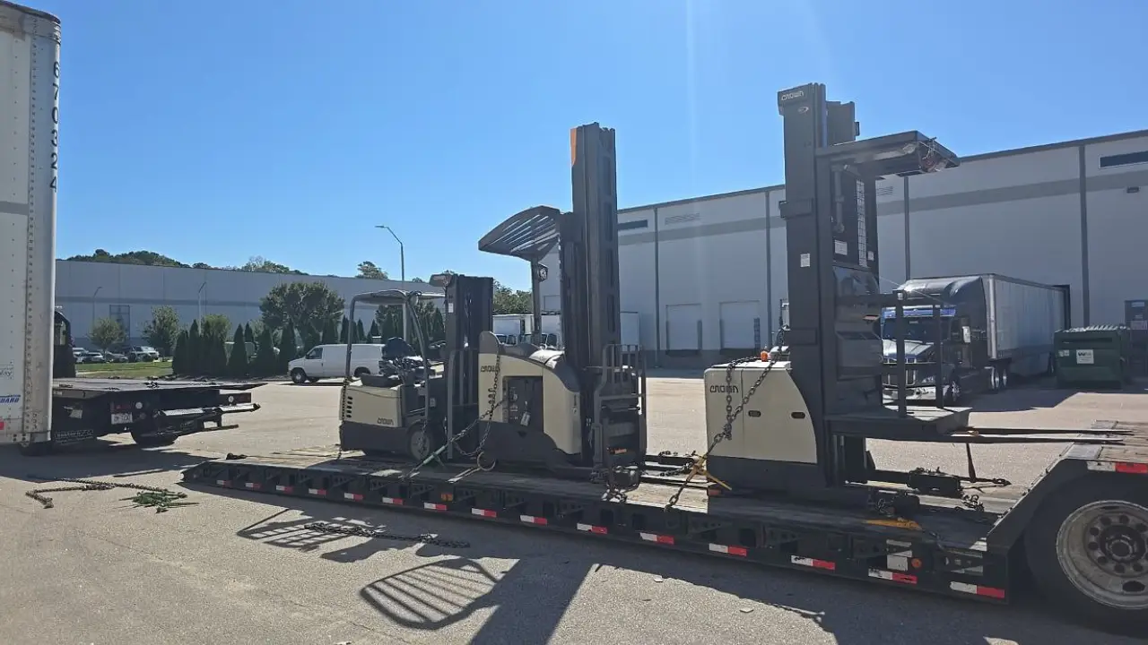 Two Crown electric forklifts loaded side-by-side on a flatbed trailer for transport by AutoStar Transport Express.
