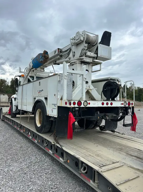 Heavy-duty utility truck securely loaded on a flatbed trailer for transport by AutoStar Transport Express.