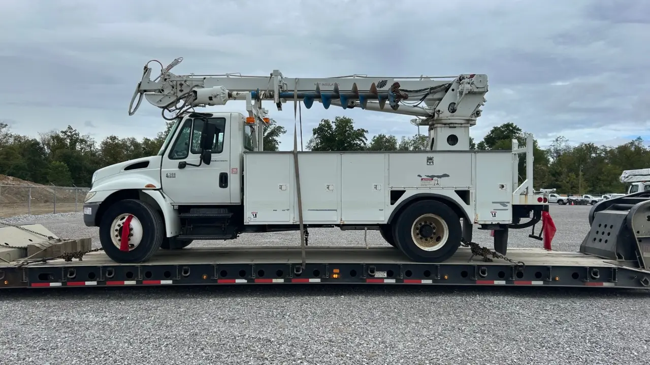 International digger derrick truck with auger secured on flatbed by AutoStar Transport Express