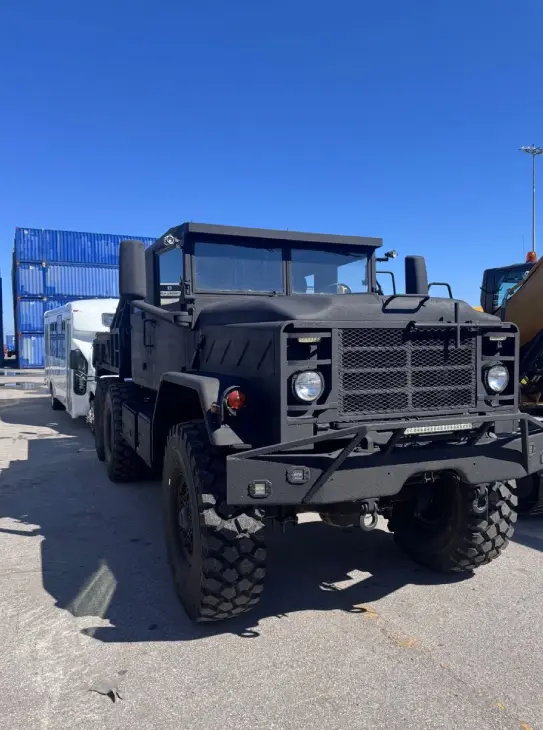 Heavy-duty tactical military truck (M939) being prepared for specialized transport by AutoStar Transport Express at a port.